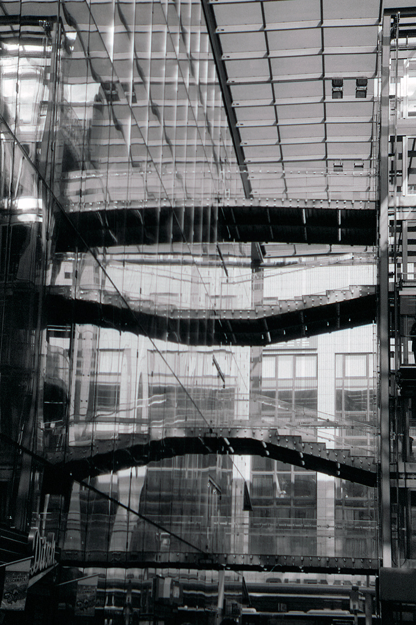 hanging stairs span from left to right inside the glass-walled department in chemnitz, reflected repeatedly in the glass facade.